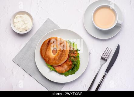 Fotografia gastronomica di bagel con salmone affumicato, panna, aneto, lattuga romaine, tè con latte, sandwich, mattina, fette, colazione, brunch Foto Stock