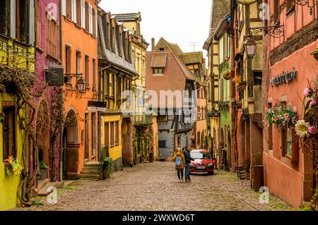 RIQUEWIHR, FRANCIA - 30 MARZO 2024: Persone che camminano tra case in legno Foto Stock