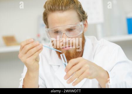 uomo in camice da laboratorio con una pipetta Foto Stock