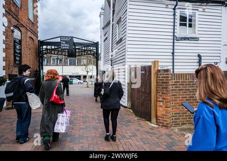 Epsom Surrey, Regno Unito, 02 aprile 2024, Small Group of People Carry Shopping Bags Walking Woman Using a Mobile Phone texting Foto Stock