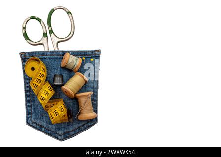 Materiali di consumo per cucire su sfondo bianco. Forbici, ditale, aghi e fili si trovano su un pezzo di denim strappato Foto Stock