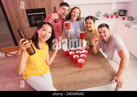 Gruppo di giovani amici che giocano a beer pong alla festa Foto Stock
