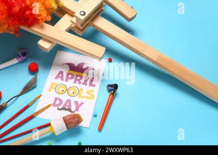 Cartolina con testo "APRIL FOOLS DAY", strumenti dell'artista e fischietti di festa su sfondo colorato Foto Stock