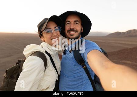 Felice giovane coppia che si fa selfie insieme sul paesaggio desertico Foto Stock