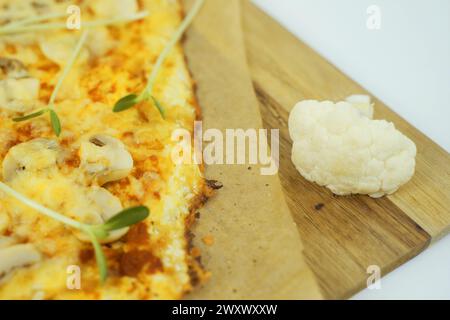 Una vista ravvicinata di una pizza appena sfornata poggiata su un tagliere di legno, che mostra i suoi deliziosi condimenti e crosta croccante. Foto Stock