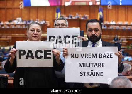 Bucarest, Romania. 2 aprile 2024: Senatrice Diana Iovanovici Sosoaca (L), presidente del partito populista di destra SOS Romania, seguiti da altri due colleghi parlamentari che mostrano alle telecamere i manifesti che dicono "Pace” e "non vogliamo basi militari straniere” dopo che hanno protestato durante la solenne riunione congiunta della camera dei deputati e del Senato del Parlamento rumeno in occasione del ventesimo anniversario di l'adesione della Romania all'Alleanza del Nord Atlantico e il 75° anniversario dell'esistenza della NATO. Crediti: Lucian Alecu/Alamy Live News Foto Stock