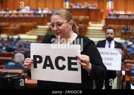 Bucarest, Romania. 2 aprile 2024: Senatrice Diana Iovanovici Sosoaca (L), presidente del partito populista di destra SOS Romania, seguiti da altri due colleghi parlamentari che mostrano alle telecamere i manifesti che dicono "Pace” e "non vogliamo basi militari straniere” dopo che hanno protestato durante la solenne riunione congiunta della camera dei deputati e del Senato del Parlamento rumeno in occasione del ventesimo anniversario di l'adesione della Romania all'Alleanza del Nord Atlantico e il 75° anniversario dell'esistenza della NATO. Crediti: Lucian Alecu/Alamy Live News Foto Stock