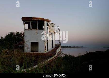 Vecchia barca abbandonata sulle rive del fiume. Vista dell'alba. Foto Stock