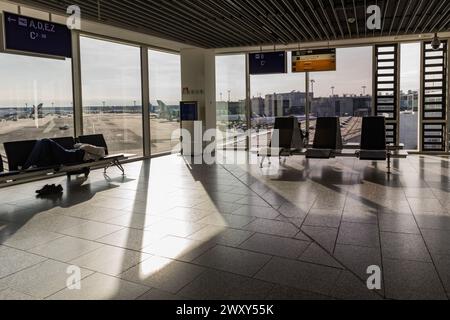 Francoforte, Assia, Germania - 17 marzo 2024. Aeroporto di Francoforte. All'interno del Terminal C dell'aeroporto di Francoforte. Un uomo riposa e aspetta un aereo connesso Foto Stock