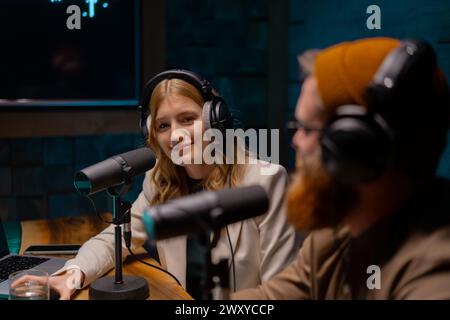 un uomo e una donna sono seduti davanti ai microfoni in uno studio. Concetto di studio di podcast Foto Stock