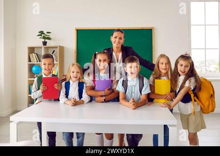 Ritratto di gruppo di studenti di primo grado con un'amichevole insegnante femminile in classe scolastica. Foto Stock