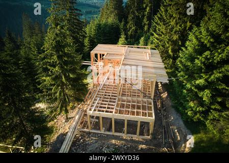 Vista droni della casa a due piani con struttura in legno in costruzione vicino alla foresta. Idea di moderna costruzione ecologica e design architettonico contemporaneo. Foto Stock