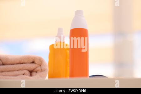 Due bottiglie arancioni con crema solare sdraiato sulla spiaggia vicino asciugamani closeup Foto Stock