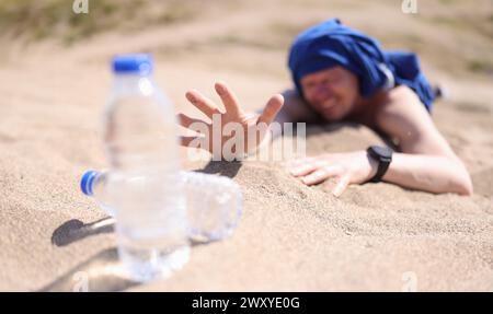 Uomo disidratato strisciato sulla sabbia per bottiglia di acqua potabile closeup Foto Stock