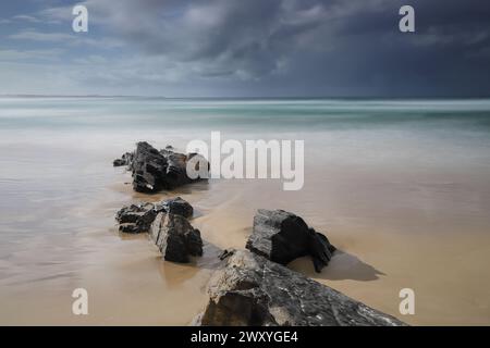 Scogli a Cabarita Beach con un temporale in avvicinamento Foto Stock