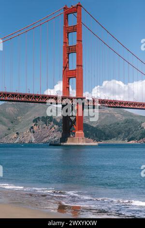 Una splendida vista del Golden Gate Bridge visto dalle spiagge sabbiose, con dolci onde che si infrangono sulla spiaggia e sulle colline in lontananza Foto Stock