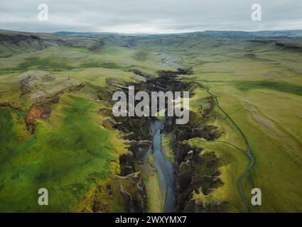 Vista aerea dello splendido canyon di Fjadrargljufur in Islanda, che mostra il tranquillo fiume che si snoda attraverso lussureggianti paesaggi verdi e aspre scogliere. Foto Stock