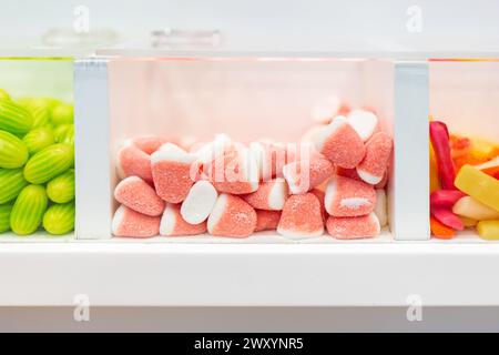 Caramelle assortite in dispenser trasparenti, con fette di anguria al centro del palco Foto Stock