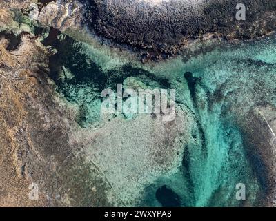 Una foto dall'alto cattura l'incredibile contrasto tra la costa frastagliata e le acque marine trasparenti e acquatiche Foto Stock