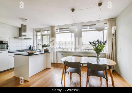 Cucina moderna e luminosa con zona pranzo integrata, design minimalista e ampia illuminazione naturale. Foto Stock