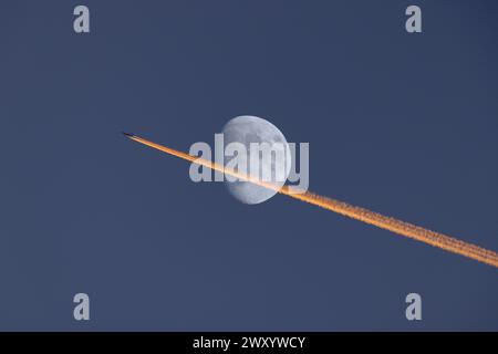 Aereo di linea con una contrada arancione-rossa illuminata dal tramonto di fronte a una luna crescente, Germania, Baviera, Flughafen Muenchen Foto Stock