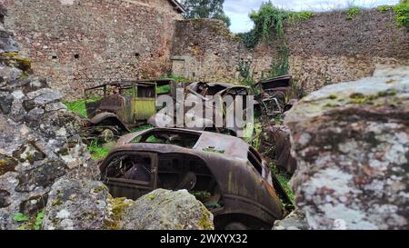 Cimitero di auto abbandonate nella città fantasma di Oradour Sur Glane. Probabilmente era un laboratorio distrutto durante la guerra. Le auto sono arrugginite Foto Stock