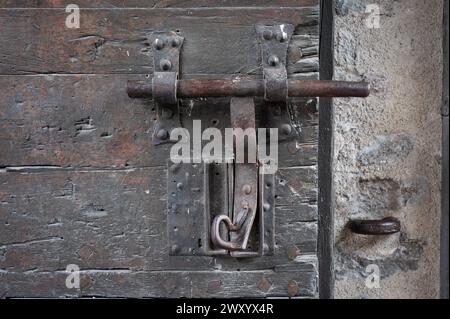 Dettaglio del vecchio bullone o dispositivo di chiusura realizzato nella forgia di una vecchia porta medievale in legno Foto Stock