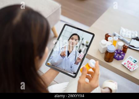 Senior donna asiatica videochiamata con medico su tablet, consultazione problemi di salute e farmaci online. Concetto medico di telemedicina Foto Stock