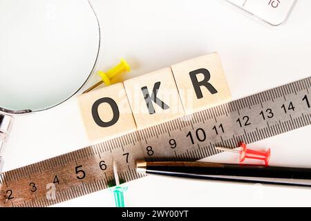 OKR . Obiettivi e risultati chiave concetto OKR su cubi in legno vicino a un righello di misurazione, lente di ingrandimento, calcolatrice. Foto Stock