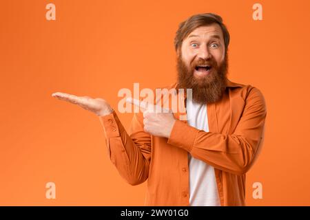 Uomo eccitato con barba rossa che punta al suo Palm, Studio Foto Stock