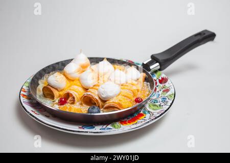 Frittelle con meringa e frutti di bosco in padella su sfondo bianco. Foto Stock