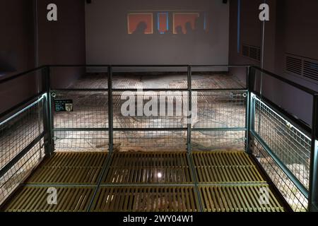 Passerella all'interno della grande sala da pranzo (triclinium) con pavimento a mosaico e proiezione di commensali romani sullo sfondo della Chedworth Roman Villa, Regno Unito Foto Stock