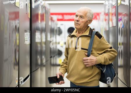 Pensionato Senor MAN che acquista un frigorifero nello showroom del negozio di elettrodomestici Foto Stock