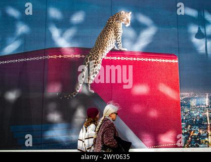 Vienna, Austria, Austria. 3 aprile 2024. Una pubblicità Cartier nel mezzo di Vienna con un leopardo sovradimensionato in piedi su una scatola e persone che camminano davanti alla pubblicità. (Credit Image: © Bianca Otero/ZUMA Press Wire) SOLO PER USO EDITORIALE! Non per USO commerciale! Foto Stock