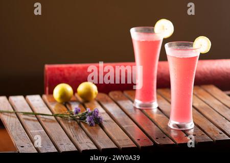 Due bicchieri di rinfrescanti cocktail rossi con fette di lime su un tavolo di legno. Foto Stock