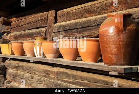 Una fila di vecchi vasi di argilla su un ripiano in legno con messa a fuoco selettiva Foto Stock