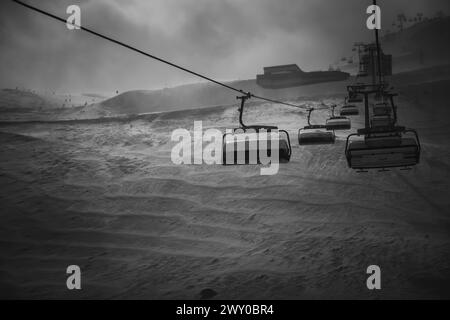 Skilift in una giornata tempestosa che sale sulla montagna, in bianco e nero Foto Stock