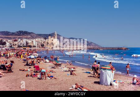 Spiaggia di Ribera a Sitges, Spagna, nell'agosto 1965. Edifici non sviluppati sul lungomare con la chiesa Església de Sant Bartomeu i Santa Tecla oltre. Platja de la Ribera Foto Stock