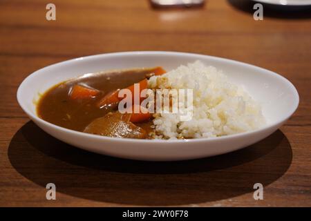 Curry giapponese con riso in un piatto bianco su un tavolo di legno Foto Stock