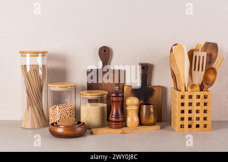 Set di vasetti in vetro con coperchio in bambù, tagliere, utensili da cucina in legno con piano cottura. Stile ecologico. Vista frontale Foto Stock