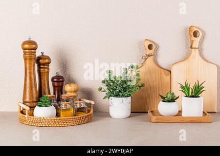 Splendido sfondo della cucina in tonalità beige con un set di contenitori per spezie, mulini in legno per spezie e vasi di piante verdi. Una cucina senza rifiuti Foto Stock