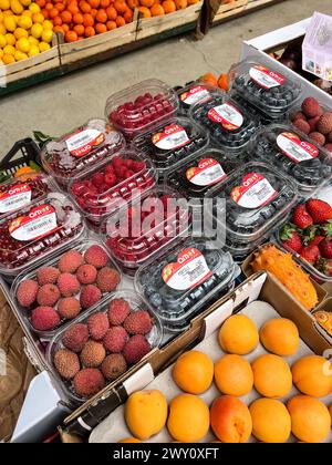 Budva, Montenegro - 25 dicembre 2022: Bacche di litchi freschi, pesche, correnti, mirtilli lampone in scatole si trovano sul bancone Foto Stock