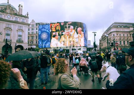 Le persone si riuniscono a Piccadilly Circus, Londra, dove un'immagine dell'incoronazione viene visualizzata su un grande schermo. Foto Stock