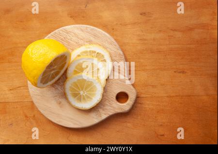 Mezzo limone e fette di limone fresco su un tagliere rotondo di legno Foto Stock