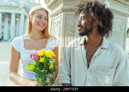 Una coppia trascorre un momento insieme, una donna con un mazzo di fiori ricevuti dal suo partner. Foto Stock