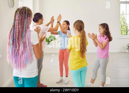 Coreografa amichevole o allenatrice sportiva che dà cinque voti alle studentesse in studio di danza. Foto Stock