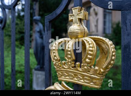 Potsdam, Germania. 3 aprile 2024. Un cancello d'ingresso con una corona dorata e la piccola portineria del Palazzo Glienicke, che fa parte della Fondazione dei Palazzi e dei Giardini prussiani Berlino-Brandeburgo (SPSG). Nel corso della tradizionale conferenza stampa annuale del 5 aprile 2024, il bilancio dell'anno passato e i piani della fondazione saranno presentati. Credito: Soeren Stache/dpa/Alamy Live News Foto Stock