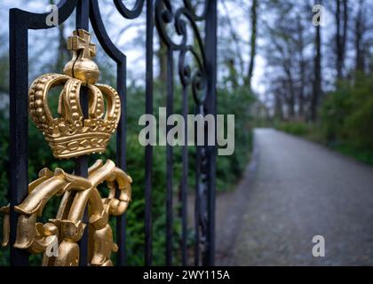 Potsdam, Germania. 3 aprile 2024. Una corona dorata sul cancello accanto alla piccola portineria del Palazzo Glienicke, che fa parte della Fondazione prussiana Palazzi e Giardini Berlino-Brandeburgo (SPSG). Nel corso della tradizionale conferenza stampa annuale del 5 aprile 2024, il bilancio dell'anno passato e i piani della fondazione saranno presentati. Credito: Soeren Stache/dpa/Alamy Live News Foto Stock