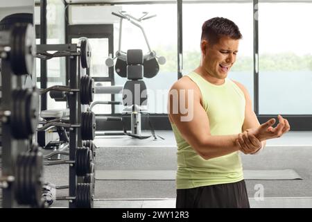 Giovane con dolore che tiene il polso in palestra, concetto di infortunio sportivo Foto Stock