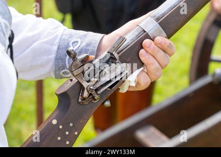 Il meccanismo di fuoco in selce di un fucile medievale in mano a un uomo Foto Stock